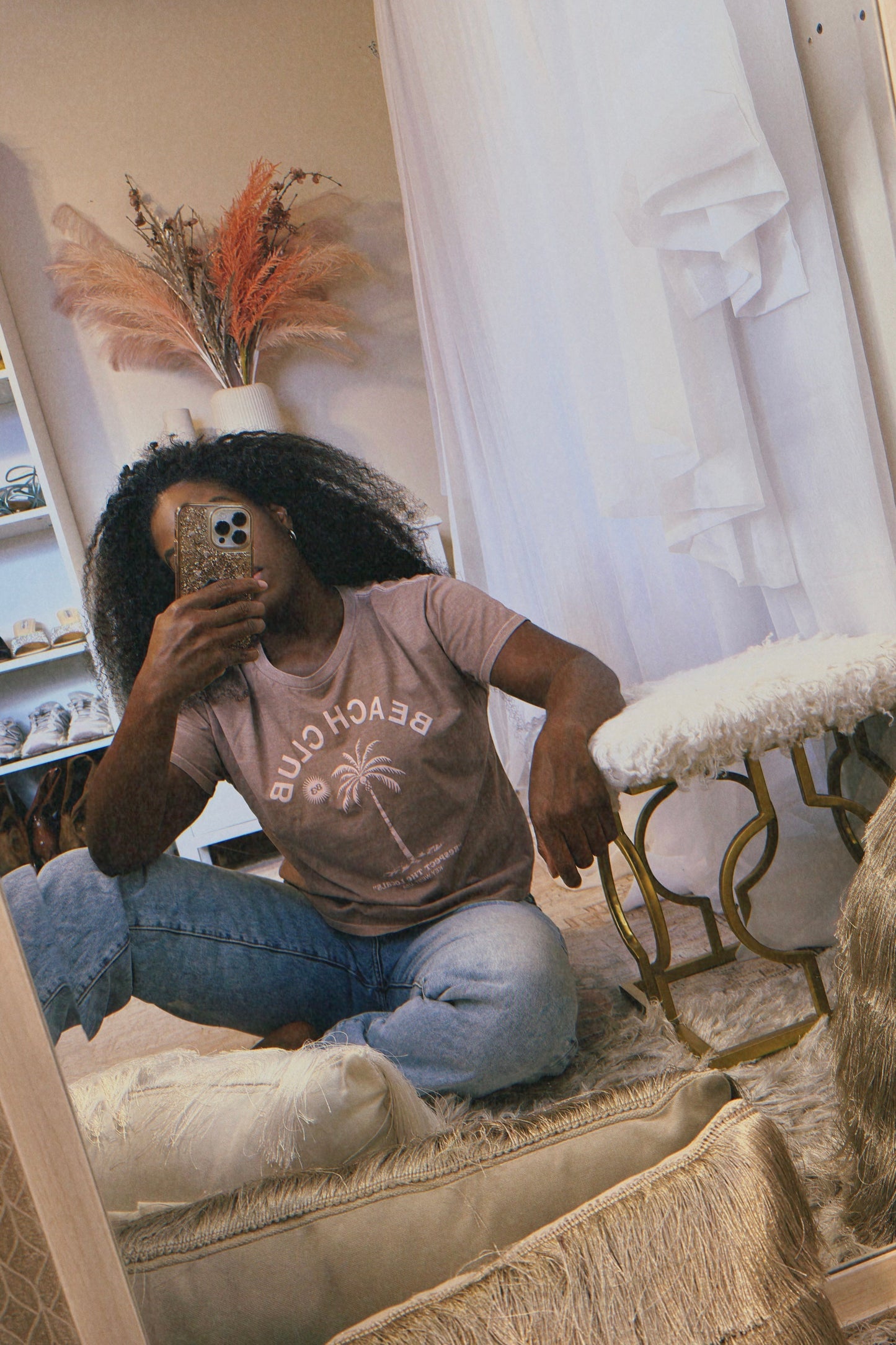 The URBN Bouquet boutique flowerbomb taking a mirror selfie in the Beach Club vintage latte colored t-shirt.