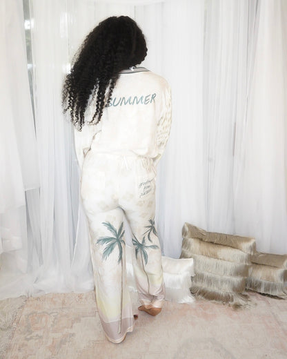 Back view of Summer Forever two piece resort pant set showing 'Summer'  text on the top and text on the back right pocket which reads 'Greetings from Paradise'.