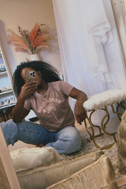 The URBN Bouquet boutique flowerbomb taking a mirror selfie in the Beach Club vintage latte colored t-shirt.