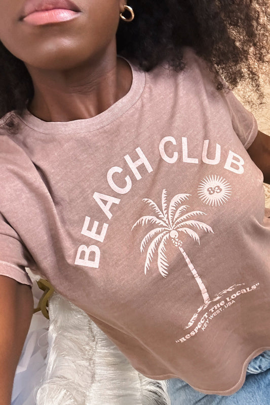 Woman wearing a 'Beach Club' t-shirt with a palm tree design.